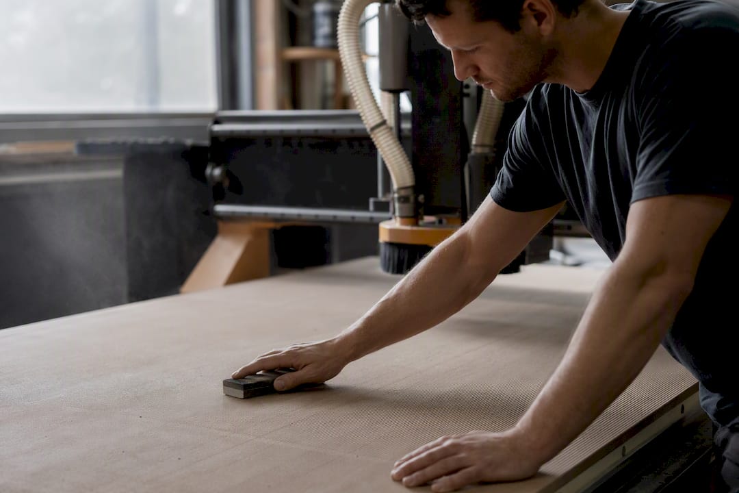 Hands resurfacing vacuum spoilboard in workshop