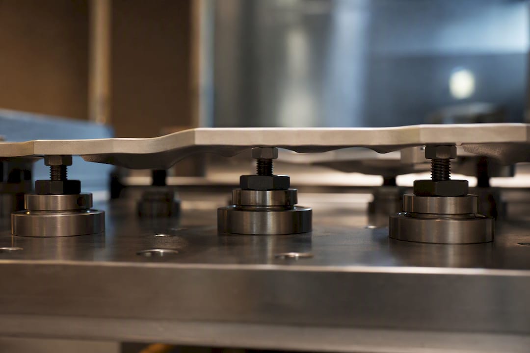 Support pads beneath a thin machined plate
